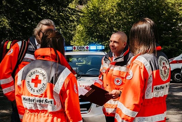 Vier Helfer vor Ort die sich vor dem Einsatzfahrzeug miteinander unterhalten