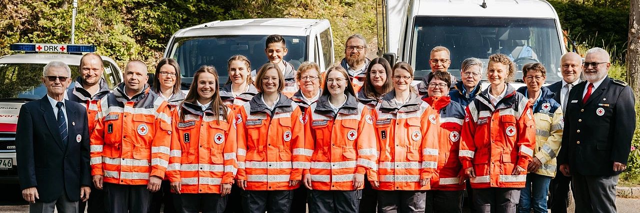 Header-OV Helfer:innen in Einsatzkleidung stehend vor den Einsatzfahrzeugen