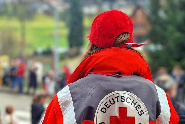 Helferin in Einsatzkleidung, von hinten gezeigt, schaut auf Fasnachtsumzug