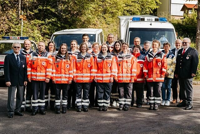 20 Helfer:innen in Einsatzkleidung stehen vor den Einsatzfahrzeugen